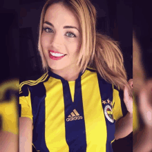 a woman wearing a yellow and blue striped adidas shirt