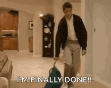 a man is walking down a hallway with a suitcase and the words `` i 'm finally done '' .