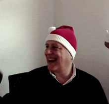 a man wearing a red and white santa hat laughs