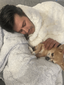 a man wrapped in a white blanket is petting his dog