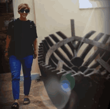 a woman wearing sunglasses and a black shirt stands in front of a wheel