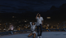 a man and a woman stand on a rooftop at night