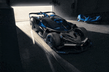 a black and blue race car is parked in a dark garage