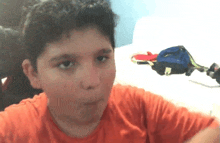 a young boy wearing an orange shirt is making a funny face