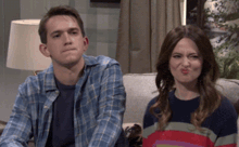 a man and a woman sit on a couch making funny faces