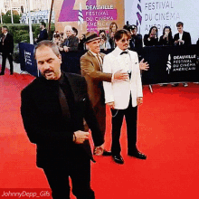 a group of men standing on a red carpet in front of a sign that says festival du cinema americain