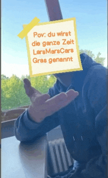 a man is sitting at a table with a note taped to his face that says pov du wirst die ganze zeit