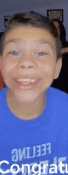 a young boy wearing a blue shirt that says congratulations is smiling .