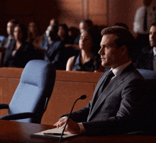 a man in a suit and tie sits at a table with a microphone