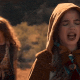 a woman wearing a hooded cape is walking with another woman