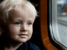 a young boy is looking out of a window on a train