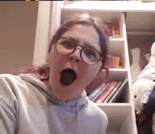 a woman wearing glasses is making a funny face with her mouth wide open