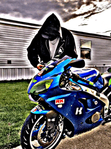 a man in a hoodie stands next to a kawasaki motorcycle