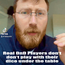 a man with glasses and a beard is holding a dice under the table