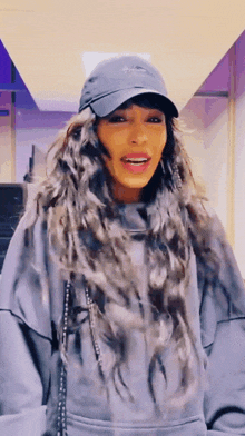 a woman wearing a hat and a hoodie is smiling