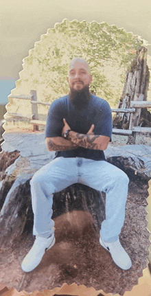 a man with a beard is sitting on a log with his arms crossed
