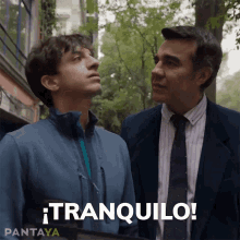 two men are standing next to each other and the word tranquilo is on the screen