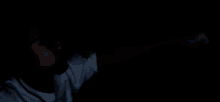 a person in a dark room with a white shirt on