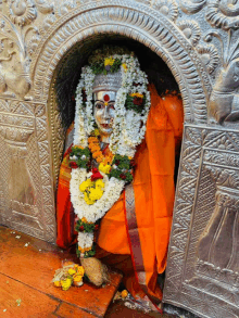 a statue of a woman with flowers around her neck is in a niche