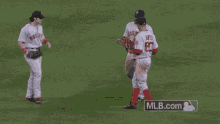 a group of baseball players are standing on a field and one of them is wearing a jersey with the number 50 on it .