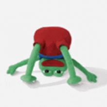 a stuffed frog is doing a handstand while wearing a red shirt