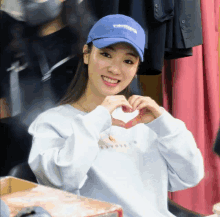 a woman wearing a blue hat making a heart shape