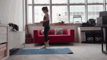 a woman stands on a yoga mat in front of a red couch with a sign that says " do not enter "