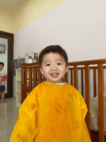 a little boy wearing a yellow apron is standing in a crib