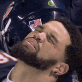 a man with his eyes closed laying next to a helmet with an american flag on it