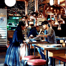 a man and a woman sit at a table in a restaurant with a sign that says toilet on it