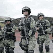 a group of soldiers are standing in a line with guns .