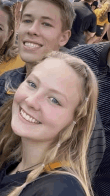 a man and a woman are smiling for the camera while sitting in a crowd of people .