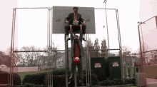 a man in a suit is sitting on a basketball hoop with a sign that says ' danger ' on it