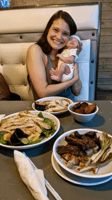 a woman is holding a baby in front of a table of food