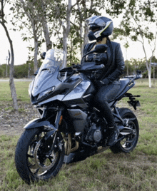 a woman wearing a helmet sits on a black motorcycle