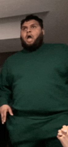 a man with a beard wearing a green turtleneck sweater