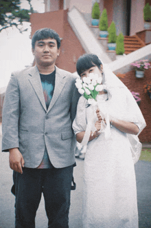 a man in a suit and a woman in a white dress pose for a photo