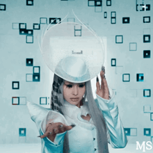 a woman with long white hair and a white hat stands in front of a wall with squares and the letters ms on the bottom