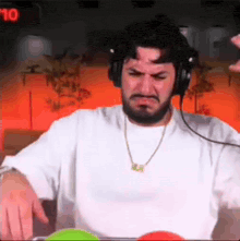 a man with a beard wearing headphones and a necklace is making a face .