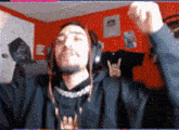 a man wearing headphones and a black hoodie is raising his fist in the air