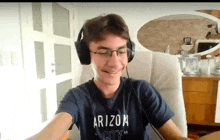 a young man wearing headphones and an arizona city shirt is smiling