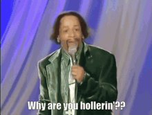 a man in a green jacket is holding a microphone and says why are you hollerin '
