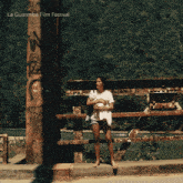 a woman holding a baby stands in front of a rusty fence with the words la guarimba film festival written above her