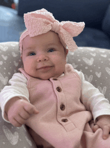 a baby wearing a pink headband and overalls is smiling for the camera