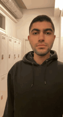 a man in a black hoodie stands in front of a row of lockers with the numbers 334 and 343 on them