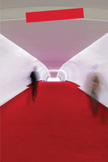 two people walking down a red carpet in a tunnel