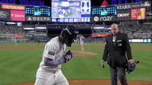 a man in a suit stands on a baseball field in front of a scoreboard that says gatorade on it