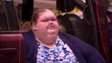 a woman is sitting in a car with a purple background