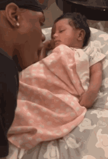 a baby wrapped in a pink and white blanket is being held by a man