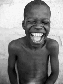 a shirtless young boy is laughing with his mouth open